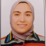 A woman wearing a headscarf and a striped shirt, smiling.