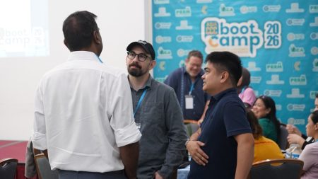 Participants at a boot camp standing around a table, actively sharing ideas