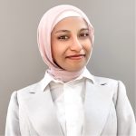 A woman dressed in a white shirt and a pink headscarf.