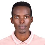 A man dressed in a pink shirt poses in front of a white background.
