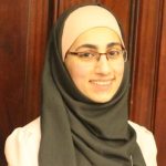 A woman wearing a black head scarf and glasses
