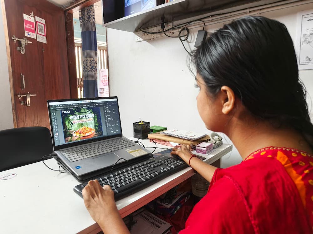 A woman sits and uses a laptop computer.