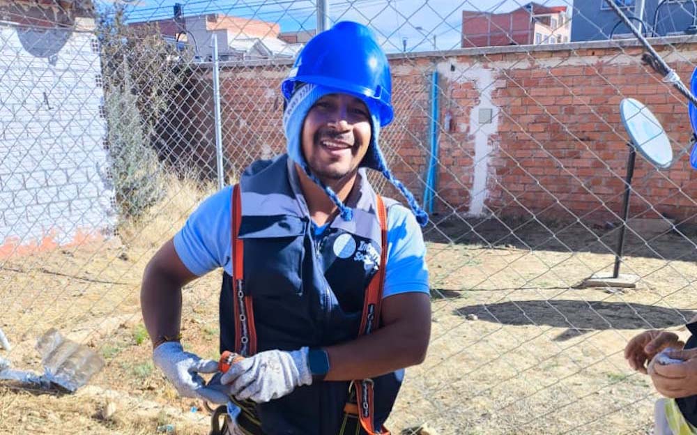 A man stands outside in a blue helmet, Internet Society vest, and other gear.