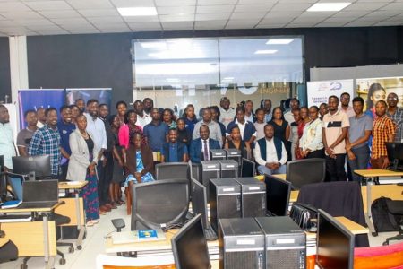 A diverse group of individuals standing in front of computers