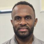 A man with a beard wearing a grey shirt.