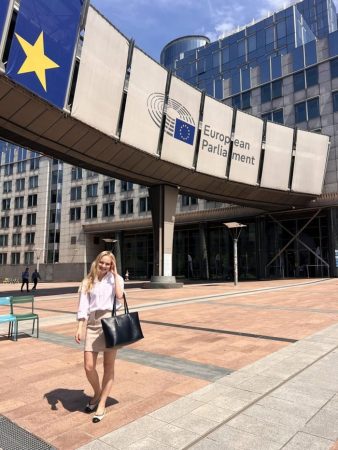 A woman stands in front of the European Parliament building