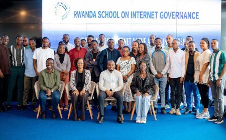 A large group of peopel gather together in front of a Rwanda School of Internet Governance sign.