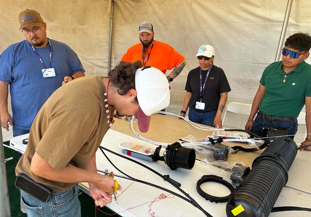 Five people stand at a table with connectivity materials.