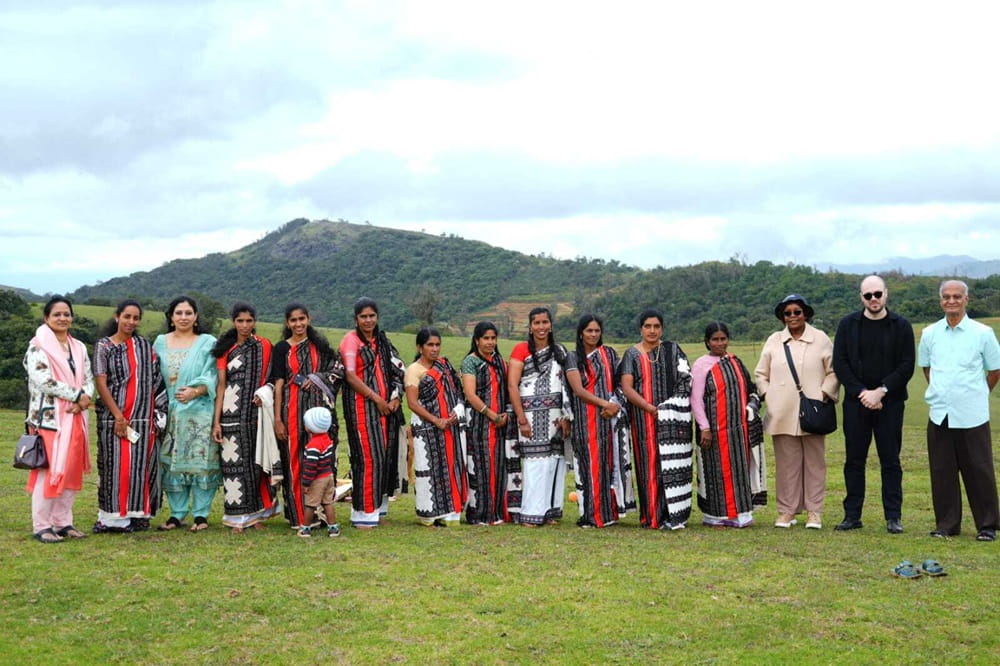 A group of individuals in traditional clothing stands together in a lush green field