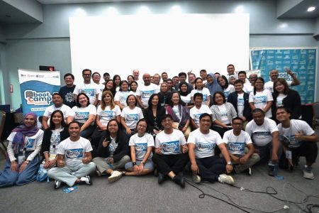 A group of individuals wearing white shirts smiles together for a photo
