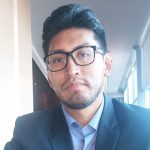 A man in a suit and glasses poses for the camera.
